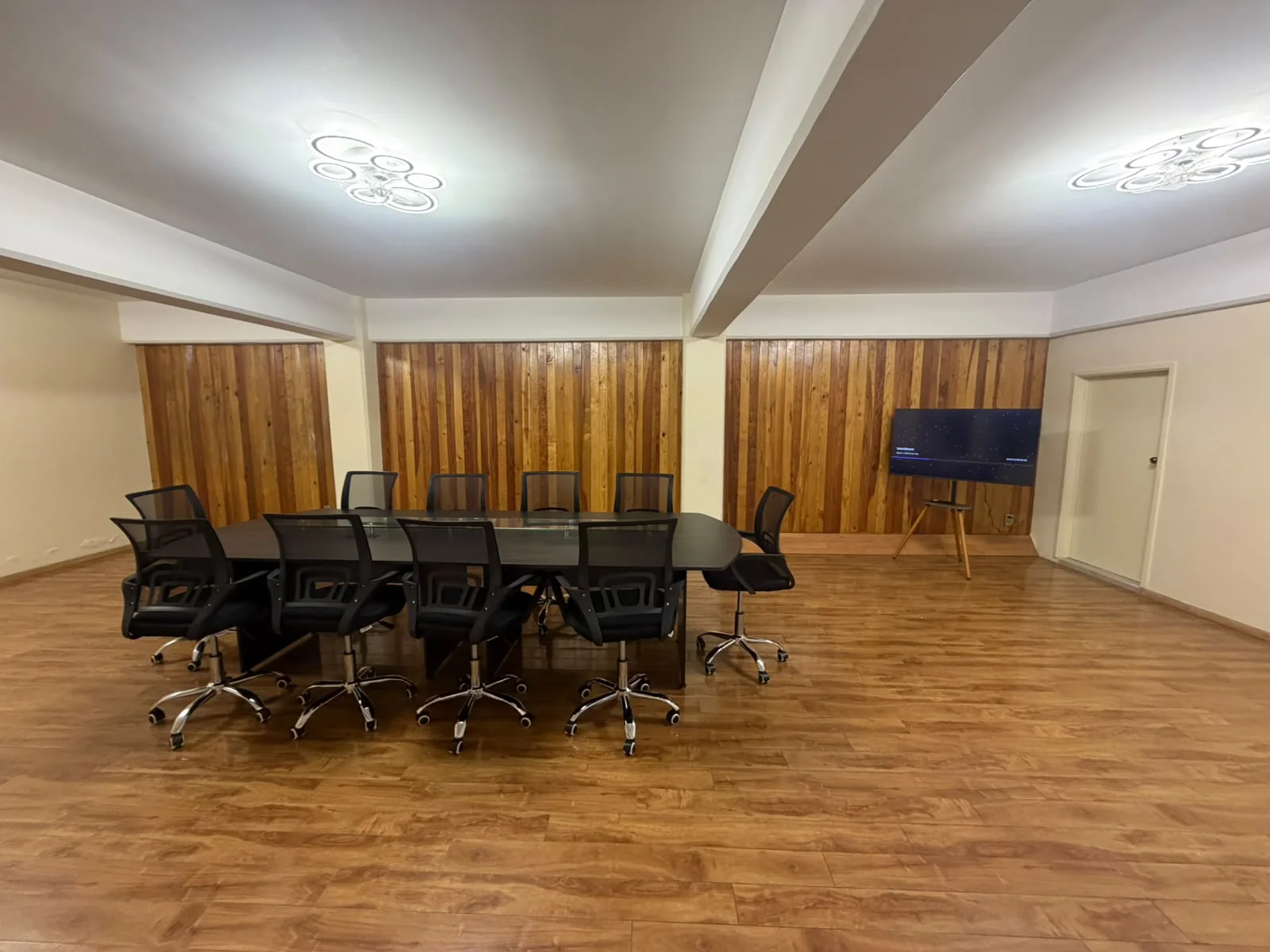 Sala de juntas con mesa amplia, sillas y pantalla